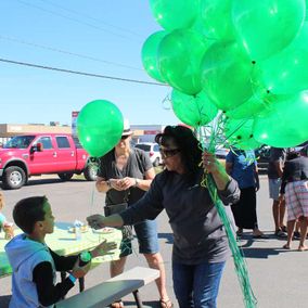 woman giving green balloon to a kid